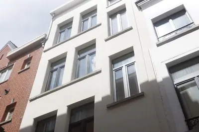 a white building with windows next to a brick building at Stadsstudio op toplocatie in Antwerp