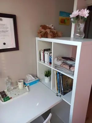 a white book shelf with books and flowers on it at Monastery Garden - 2 single and little rooms - bed & free breakfast - shared accomodation where landlord lives in Wezembeek-Oppem