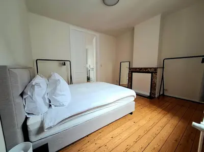 a bedroom with a bed with white sheets and pillows at La Suite Alice in Brussels