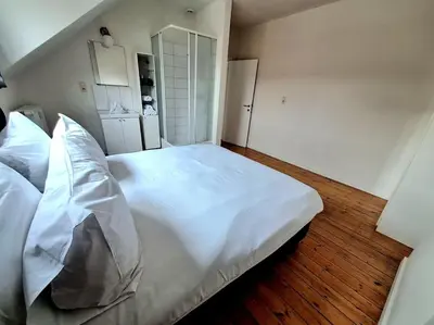 a large white bed in a bedroom with wooden floors at La Suite Julienne in Brussels