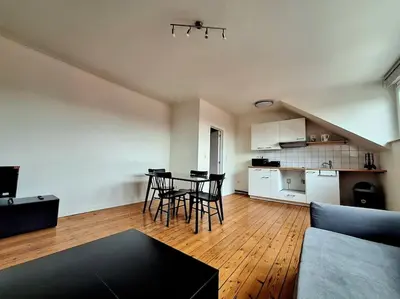 a living room with a table and chairs and a kitchen at La Suite Julienne in Brussels