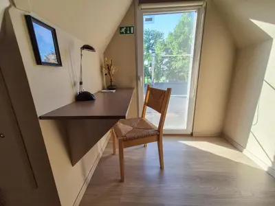 a desk and chair in a room with a window at B&B Tlekkerbeddeke in Rumst
