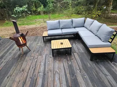 a blue couch sitting on a wooden deck with a fireplace at Casa De Los Ciervos in Stekene