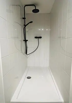 a shower in a white tiled bathroom at Clemençon by BLOSS in Ghent