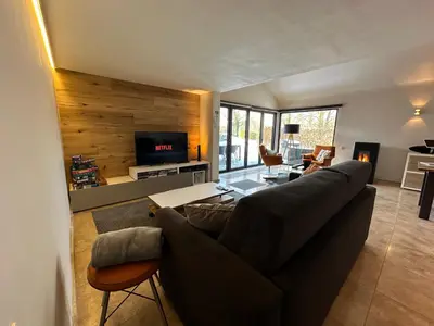 a living room with a couch and a tv at Sakura Lodging in Bossut-Gottechain