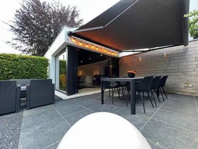 a patio with a table and chairs and a building at Sakura Lodging in Bossut-Gottechain