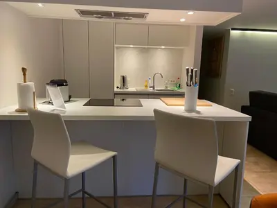 a kitchen with two white chairs and a counter with a sink at Sakura Lodging in Bossut-Gottechain