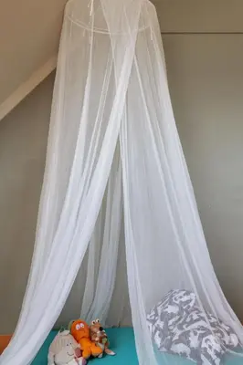 a bed with white curtains and stuffed animals on it at De Bronne in Herzele
