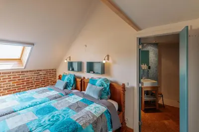 a bedroom with a large bed with blue pillows at De Bronne in Herzele
