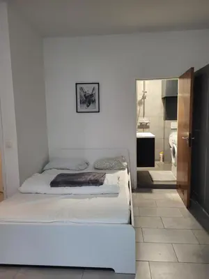 a white bedroom with a bed and a bathroom at Pleasant Studio ready for you to enjoy in Antwerp