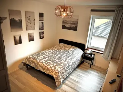 a bedroom with a bed and a window and a chandelier at hébergement pour 3 personnes, 2 chambres in Overijse