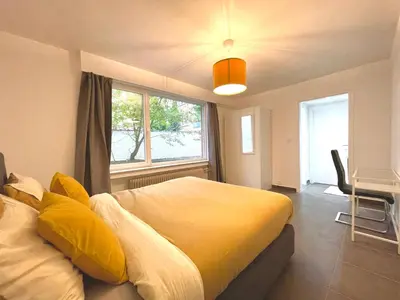 a bedroom with a large yellow bed and a window at Duden Park Brussels - Cosy APT 1 Bedroom in Brussels