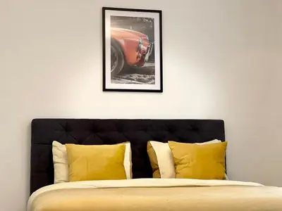 a bed with yellow pillows and a picture of a car at Duden Park Brussels - Cosy APT 1 Bedroom in Brussels