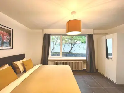 a bedroom with a large yellow bed and a window at Duden Park Brussels - Cosy APT 1 Bedroom in Brussels