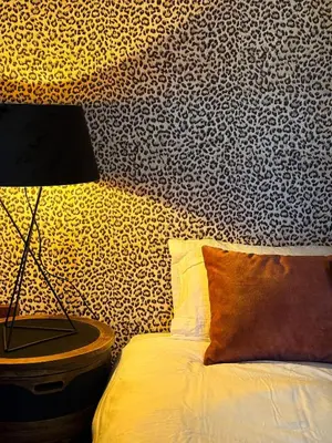 a bedroom with a bed with a lamp and a patterned wall at Cosy Boudoir Suites - 4p in Antwerp