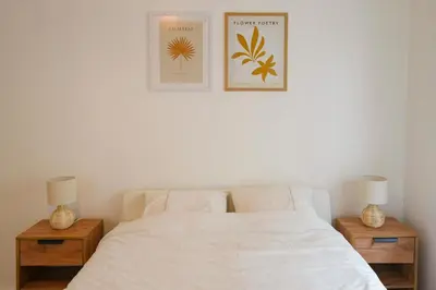 a bedroom with a bed with two nightstands and two lamps at Cocon tout chaud - Pour couple avec ou sans bébé au rez-de-chaussée in Brussels