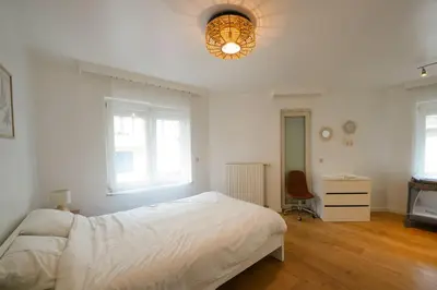 a white bedroom with a bed and a lamp at Cocon tout chaud - Pour couple avec ou sans bébé au rez-de-chaussée in Brussels