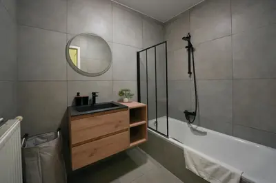 a bathroom with a sink and a tub and a mirror at Cocon tout chaud - Pour couple avec ou sans bébé au rez-de-chaussée in Brussels