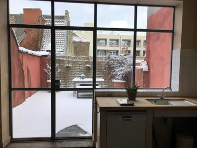 a kitchen with a window view of a snow covered yard at Spacious duplex with terrace in the middle of the center in Ghent