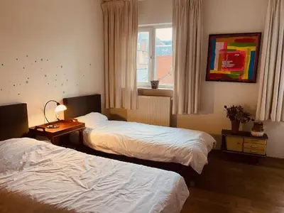 a hotel room with two beds and a window at Spacious duplex with terrace in the middle of the center in Ghent