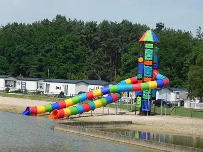 a colorful water slide in a park next to the water at Charming Breebos Getaway in Rijkevorsel