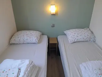 two beds in a small room with a light on the wall at Charming Breebos Getaway in Rijkevorsel
