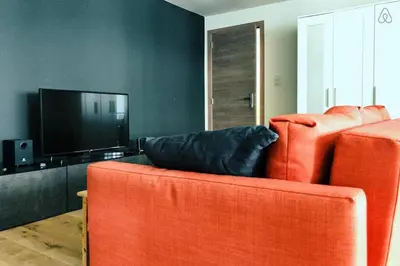 a living room with an orange couch and a flat screen tv at Fully equipped two bedroom apartment Schuman area in Brussels