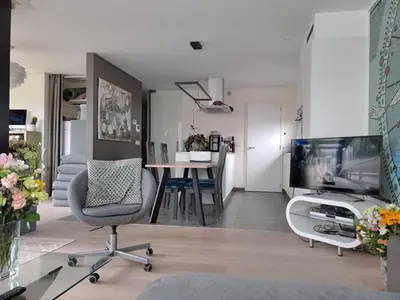 a living room with a tv and a chair and a table at Carlotta Penthouse in Ghent