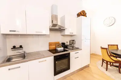 a kitchen with white cabinets and a sink and a table at Gotha Aparthotel in Brussels