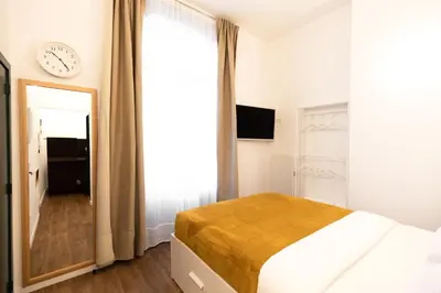 a bedroom with a bed and a clock on the wall at Gotha Aparthotel in Brussels