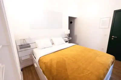 a small bedroom with a bed with a yellow blanket at Gotha Aparthotel in Brussels