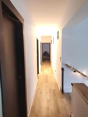 a hallway with white walls and a wooden floor at Maison Toulouse in Affligem