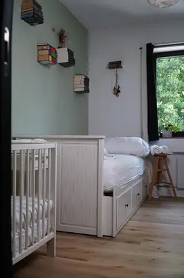 a white nursery with a crib and a window at Maison Toulouse in Affligem