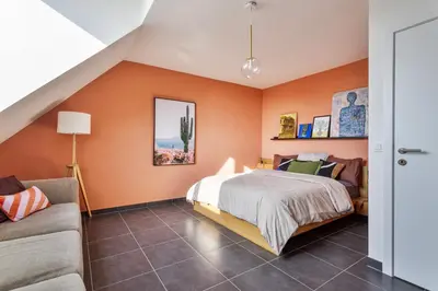 a bedroom with orange walls and a bed and a couch at Ruim 3 slaapkamer appartement met parking nabij NATO in Machelen
