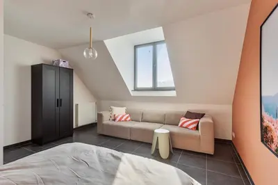 a attic room with a couch and a window at Ruim 3 slaapkamer appartement met parking nabij NATO in Machelen