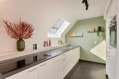 a kitchen with white cabinets and a sink at Ruim 3 slaapkamer appartement met parking nabij NATO in Machelen