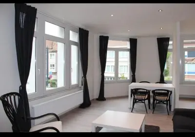 a living room with a table and chairs and windows at Voskenslaan in Ghent