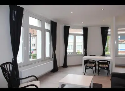 a living room with a table and chairs and windows at Voskenslaan in Ghent