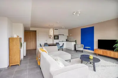 a living room with two couches and a kitchen at Ruim 2 slaapkamer appartement met parking nabij NAVO in Machelen
