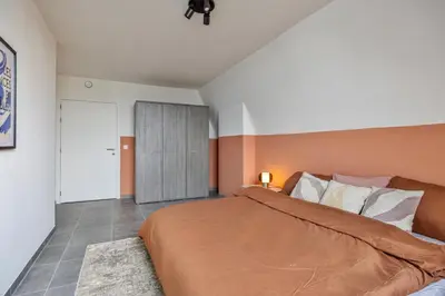 a bedroom with a large bed and a door at Ruim 2 slaapkamer appartement met parking nabij NAVO in Machelen