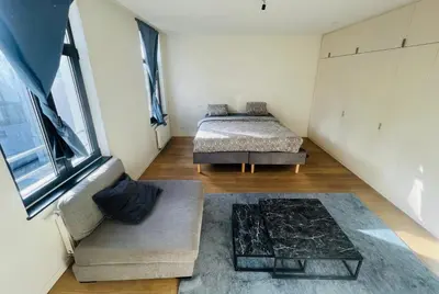 a bedroom with two beds and a couch and a window at PENTHOUSE SABLON in Brussels