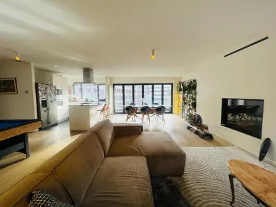 a living room with a brown couch and a kitchen at PENTHOUSE SABLON in Brussels