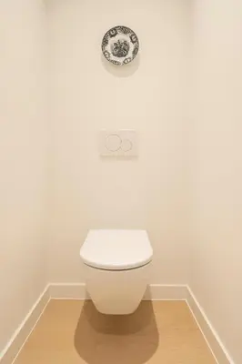 a white toilet in a bathroom with a plate on the wall at SHWAY - The Captain's View in Antwerp