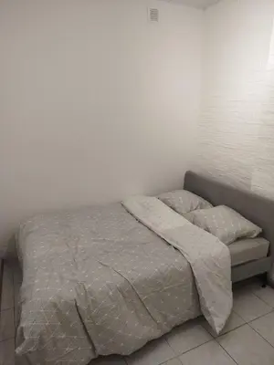 a bed in a bedroom with a white wall at Charmant logement familial au cœur d'AALST Belgique in Aalst