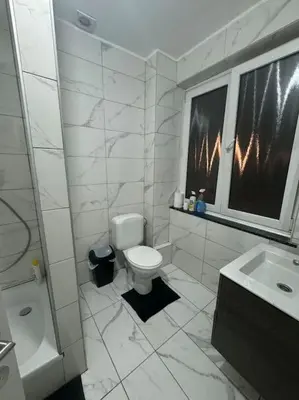 a white bathroom with a toilet and a window at Appartement à Bruxelles in Brussels