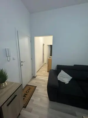 a living room with a black couch and a hallway at Appartement à Bruxelles in Brussels