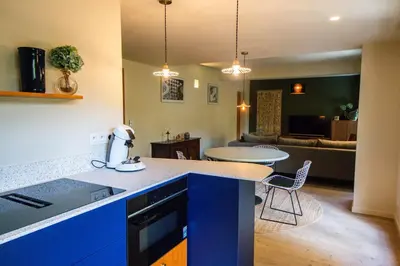 a kitchen with blue cabinets and a table and a living room at Zesdrienegen in Ghent