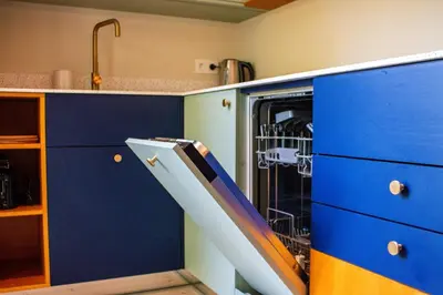a dishwasher in a kitchen with blue cabinets at Zesdrienegen in Ghent