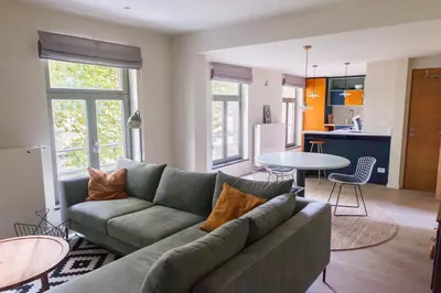 a living room with a green couch and a kitchen at Zesdrienegen in Ghent