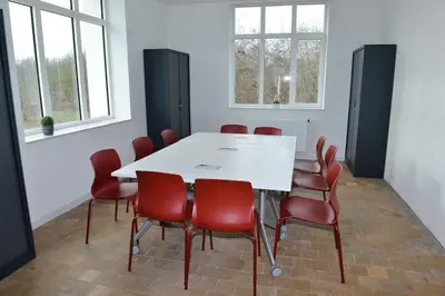 a conference room with a white table and red chairs at Jeugdverblijfcentrum Schotte in Aalst